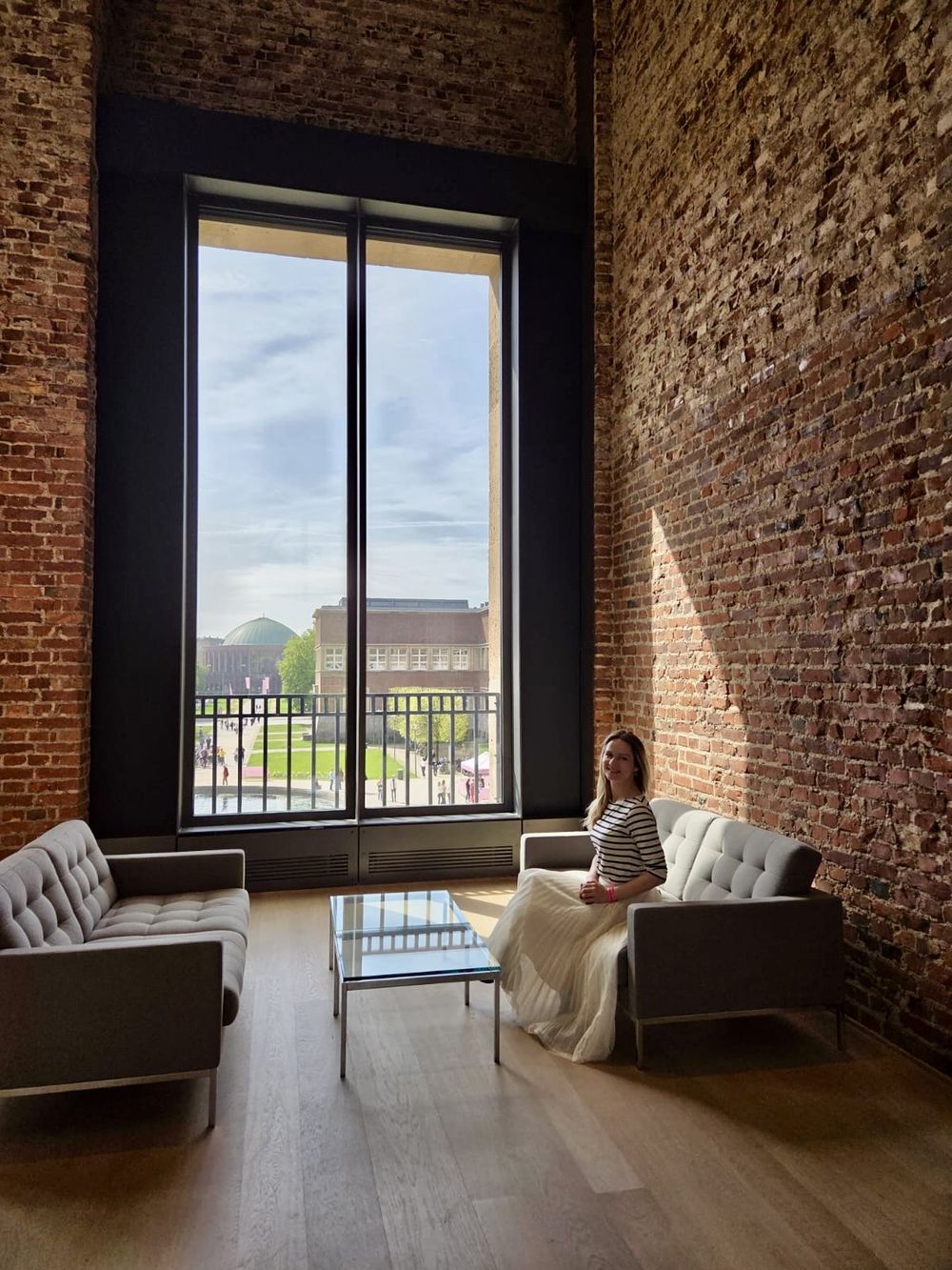 Heller Raum mit Backsteinwand, großem Fenster und zwei Sofas, die sich gegenüberstehen